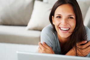 A woman sitting with a laptop and smiling at the camera