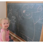 A little girl standing in front of a blackboard