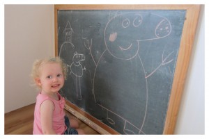 A little girl standing in front of a blackboard