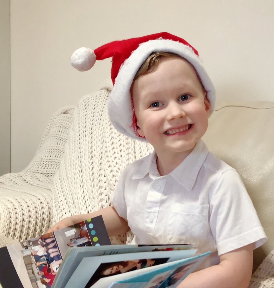 A child with Santa hat looking at a photo book
